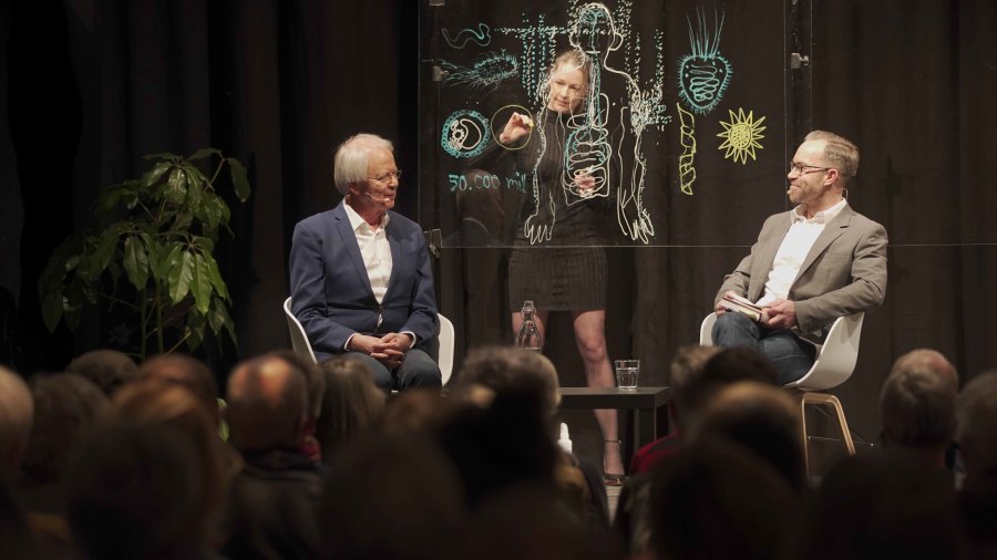 Oluf Borbye Pedersen i samtale med Lars Igum Rasmussen. Simultantegnet af Tea Bendix, musik Anders Hjernø