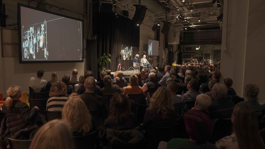 Oluf Borbye Pedersen i samtale med Lars Igum Rasmussen. Simultantegnet af Tea Bendix, musik Anders Hjernø